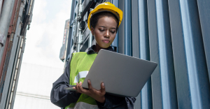 Staff member by shipping container increasing supply chain efficiency with IDP