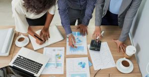 Overhead shot of three people working on multiple documents. Representing how to write an RFP.