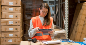 Procure-to-pay software being used by a person wearing a high-viz jacket, working in a warehouse.