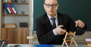 Why finance leaders must drive AI implementation now - person sat at desk pointing at an abacus.