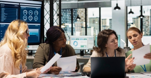 People sat around a desk with a computer on, working with SAP.